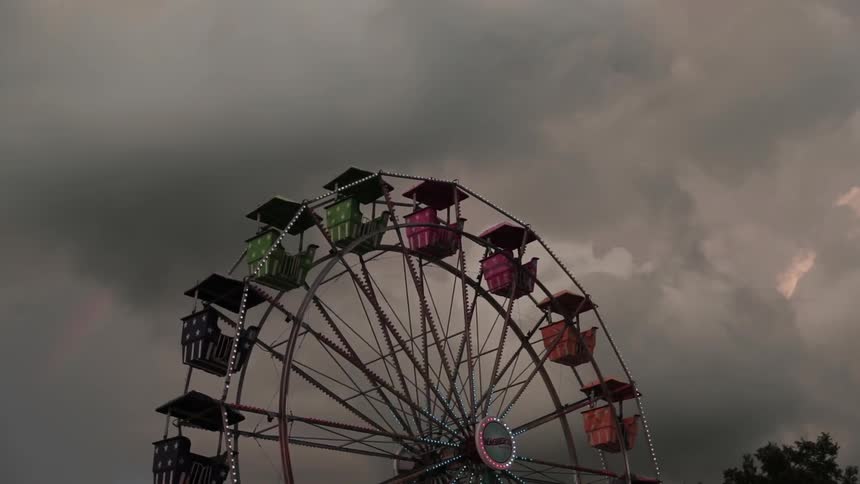 A ferris wheel lights up and turns on a cloudy day