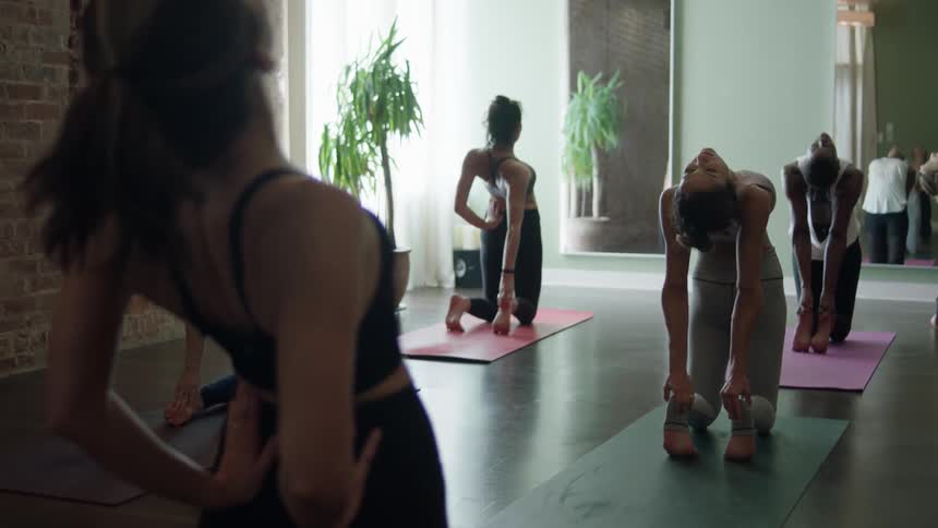 Women arch backwards as they do a yoga pose