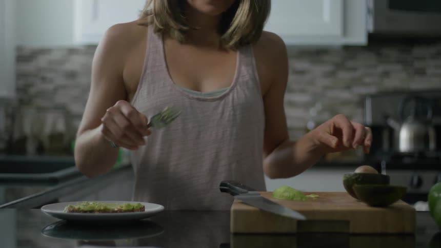 Woman licks a fork and then puts it in the sink