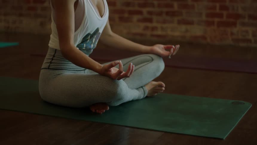 A woman is meditating on a green yoga mat