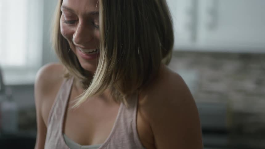 A woman smiles and laughs in the kitchen