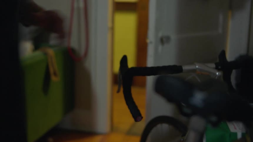 A woman opens the door and takes her bicycle out