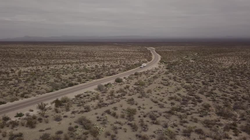 Cars drive on a long stretch of desert road