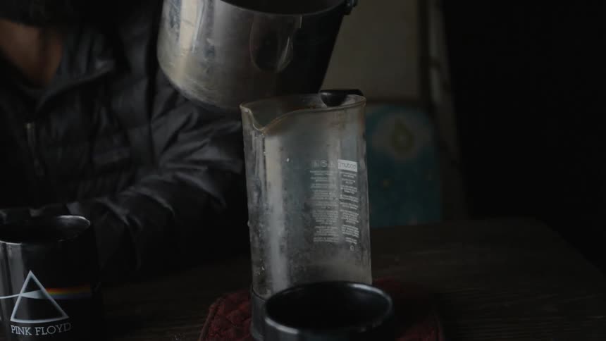 Hot water is poured from a pot into a french press carafe