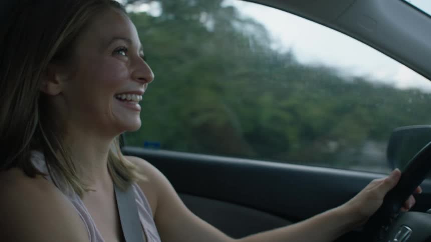 A woman laughs as she drives