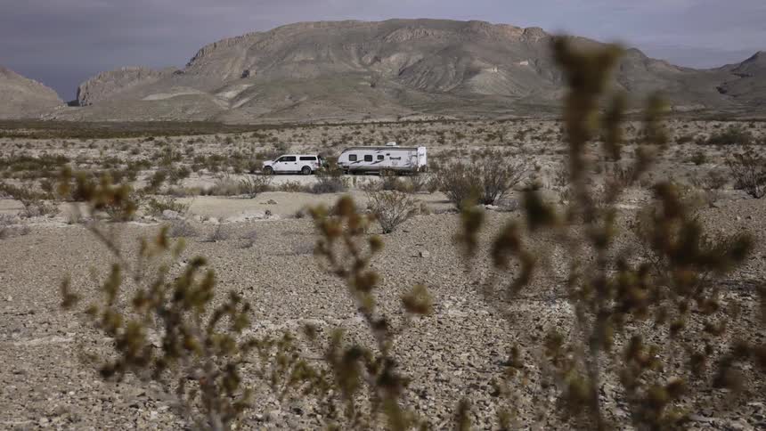 A truck with a trailer attached sits parked in the desert