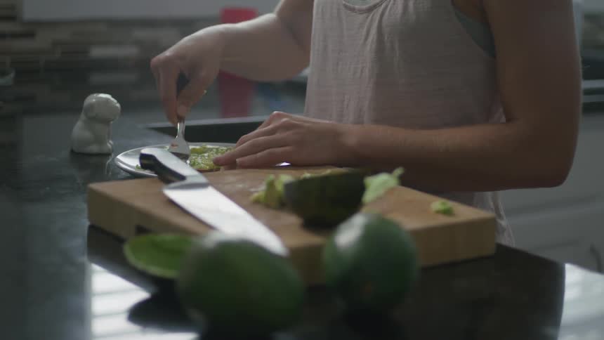A woman is preparing a sandwich in the kitchen