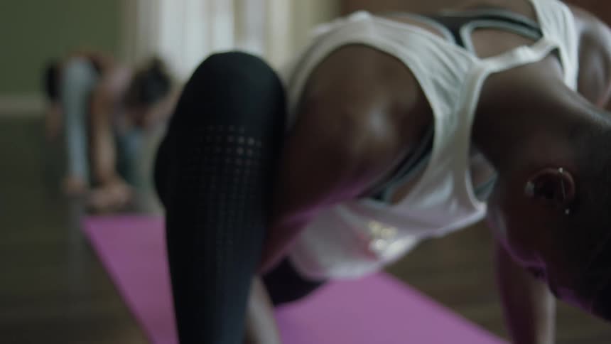 A woman stretches while doing yoga in a studio