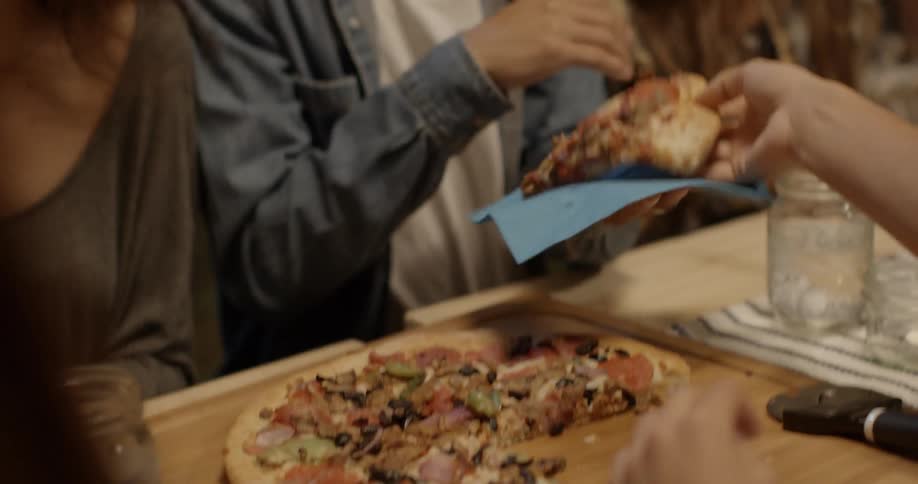 People sit down and start eating pizza