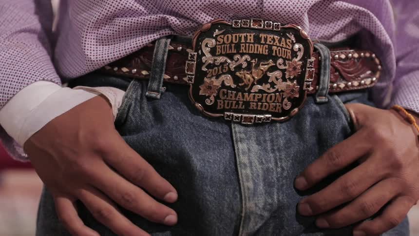 A boy wears a bull riding championship belt buckle
