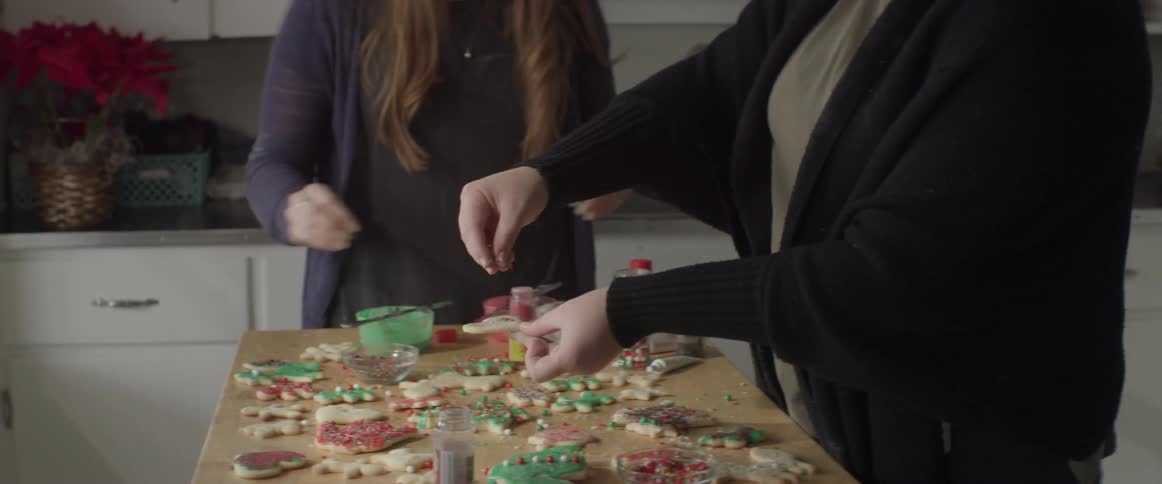 Women decorating christmas cookies with sprinkles