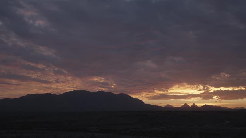 Clouds hang above the mountain landscape as the sun sets