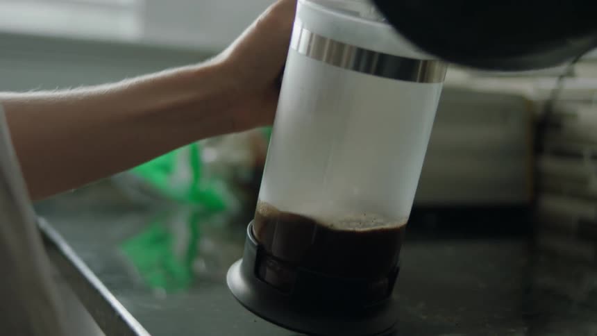 A woman pours hot water into a coffee pot