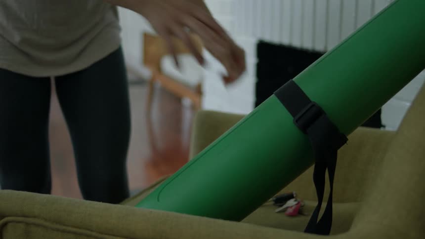 A woman walks over and grabs her yoga mat