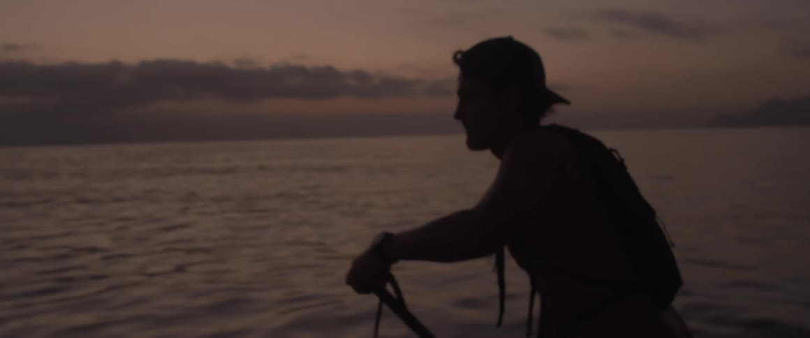 A man grabs his paddle to push the board he is on