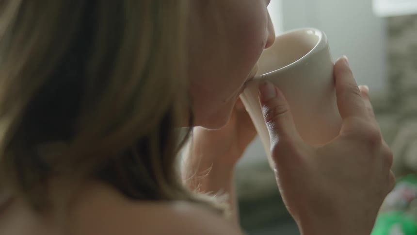 A woman holds a steaming cup of coffee