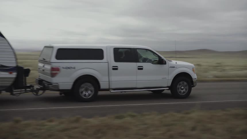 A truck is pulling a caravan down the long road