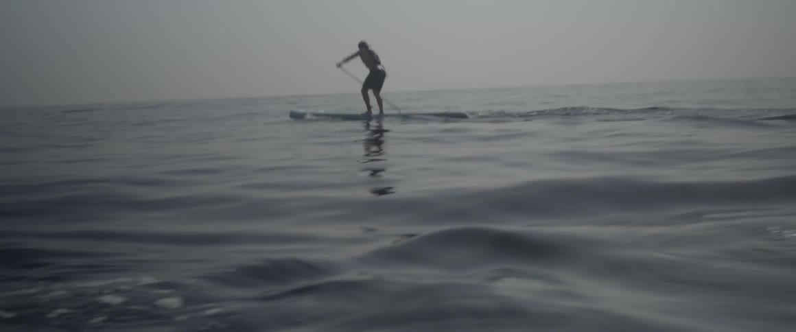 A man paddles fast on a board in the water