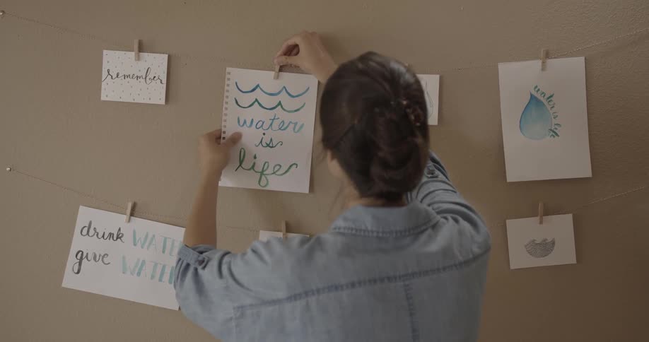A woman hangs a painting on a clothespin