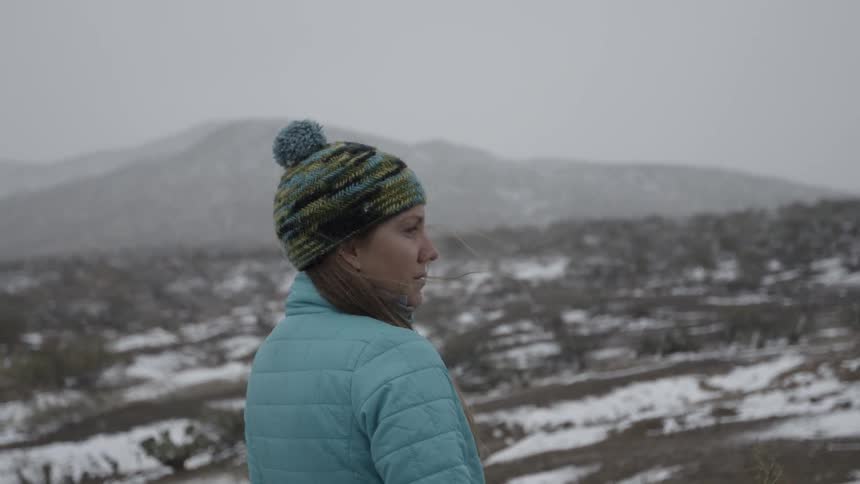 Woman stands looking outside on a snowy day
