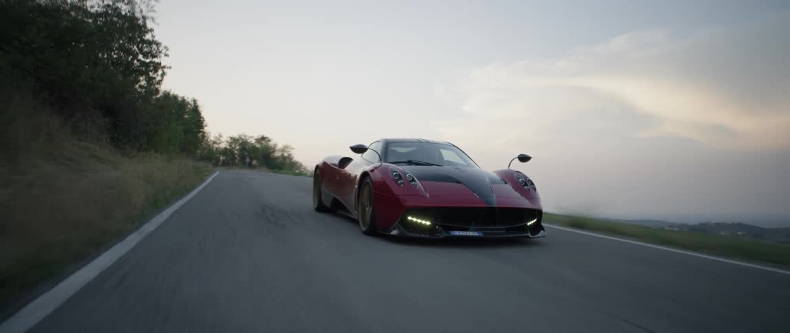 A red sports car drives fast on a winding road