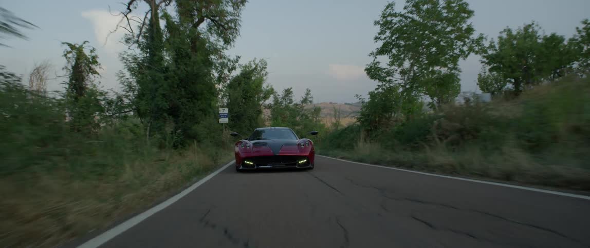 A sports car races down the narrow road