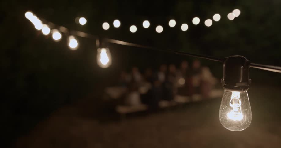 People eat beneath patio lights at night