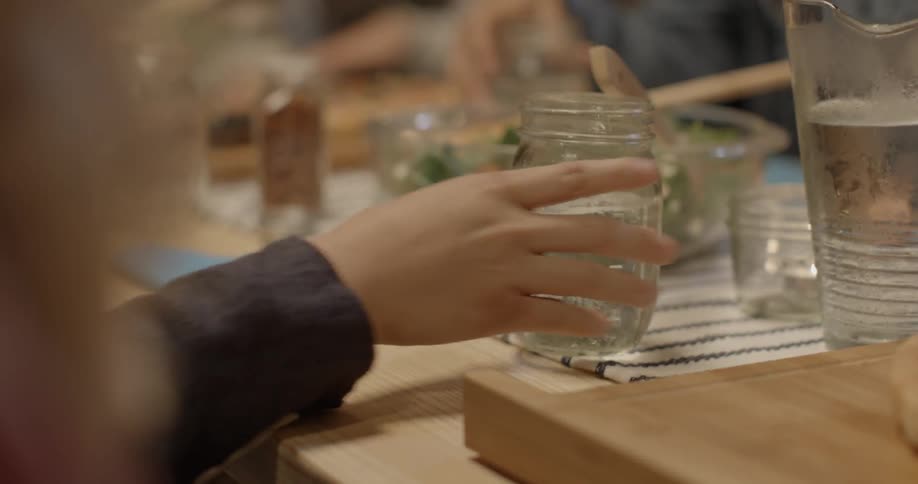 A person places a drink in a jar on the dinner table