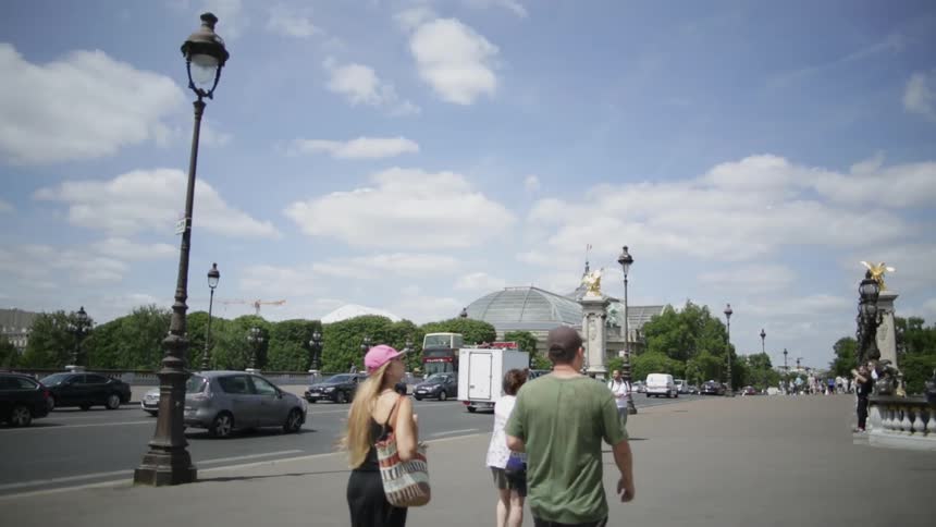 People walk on the sidewalk as cars travel in the street