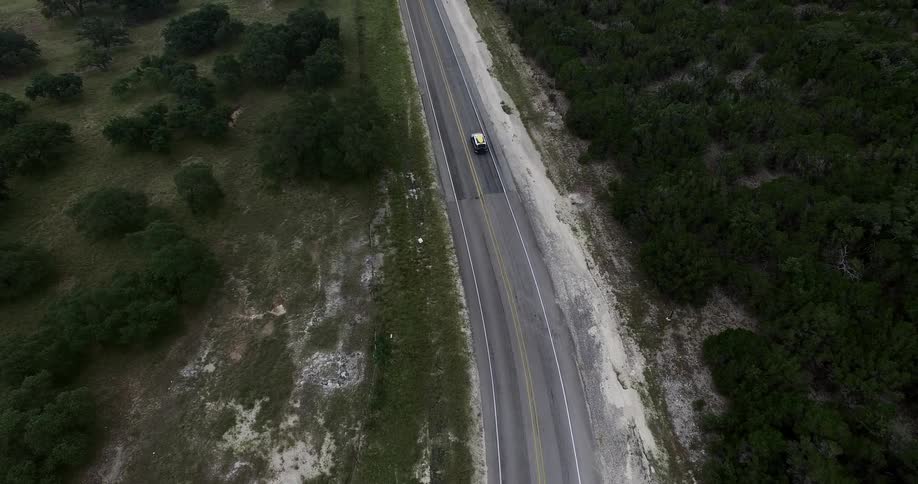 A single vehicle is driving down the road below