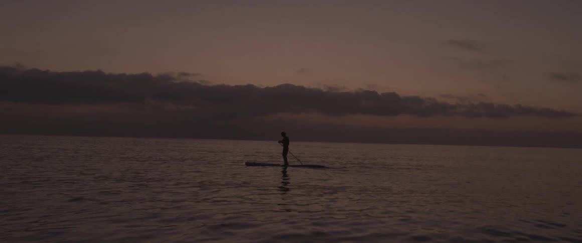 A man paddles on a board in the ocean