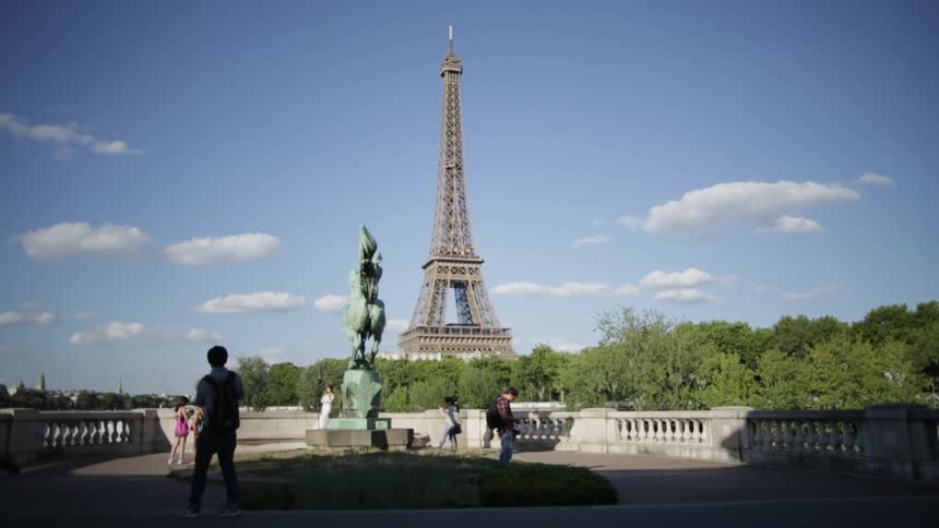People walk by a statue touring the eiffel tower
