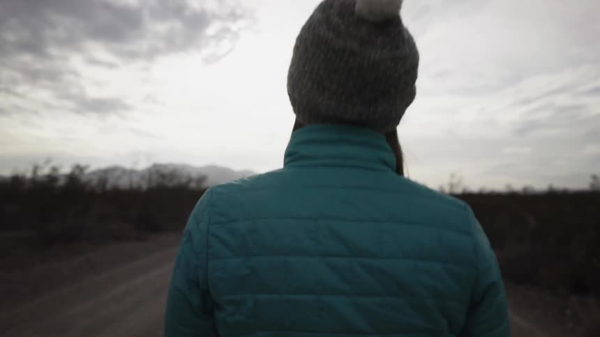 Two people walk on a rural road on a cloudy day