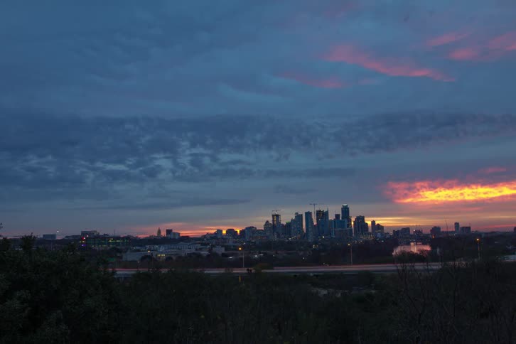 Construction cranes work in a city from dusk to dawn