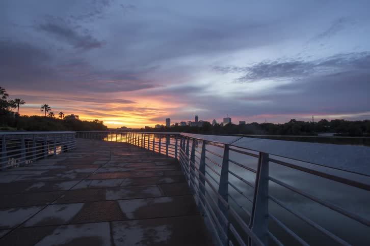 People steadily move across the boardwalk at sunset