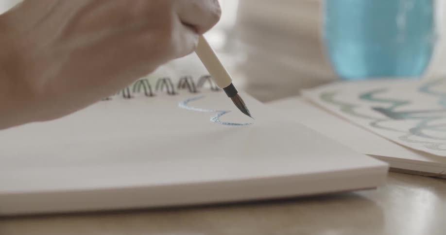 An artist paints in a notebook