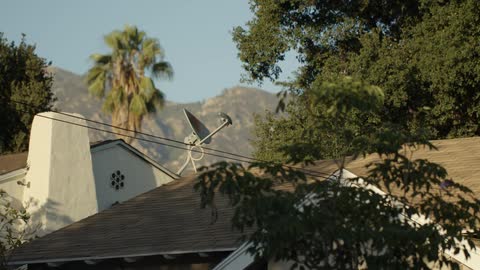 Power lines hang from a house which has a satellite dish