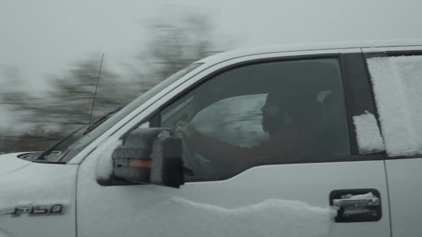 A man is driving a pickup truck on a winter day
