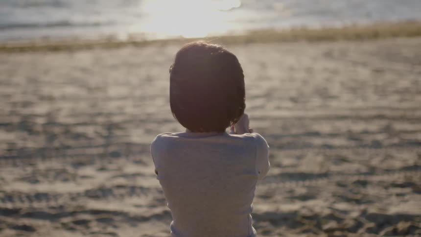 A child is pointing a gun towards the ocean