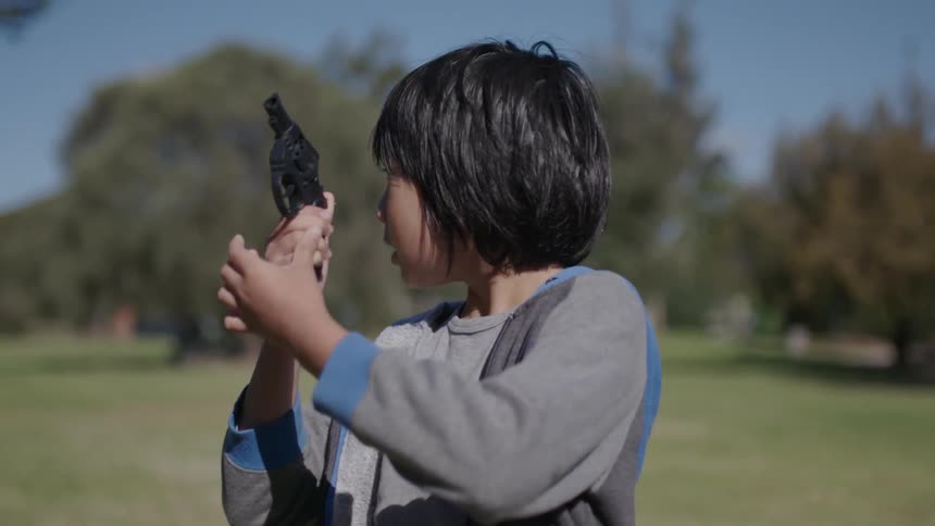 A child is holding a gun on a sunny day