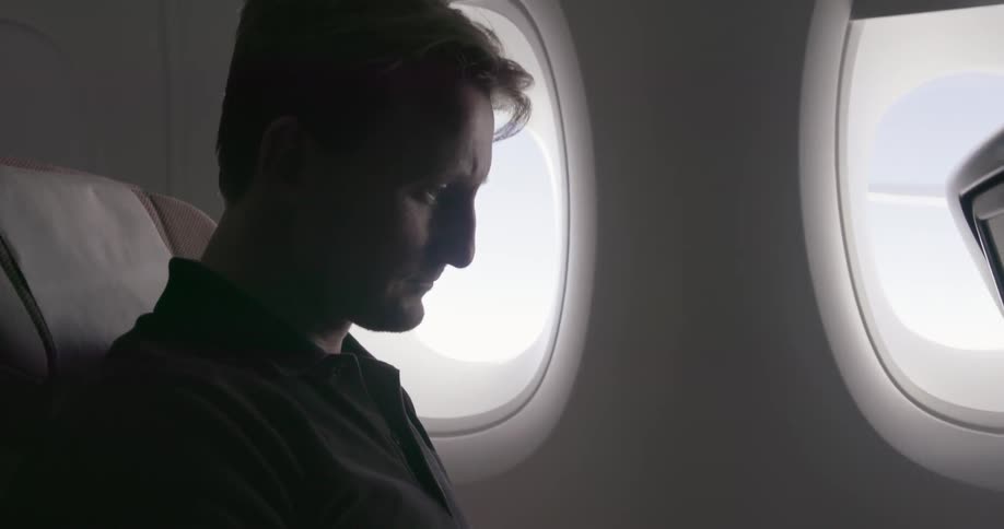 A man reads a magazine while flying in a plane