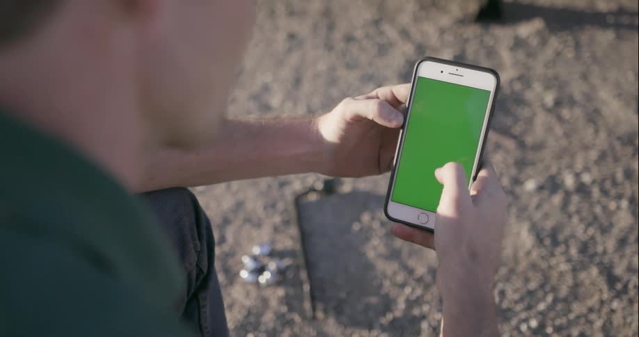 Man looks at his phone outside on a sunny day