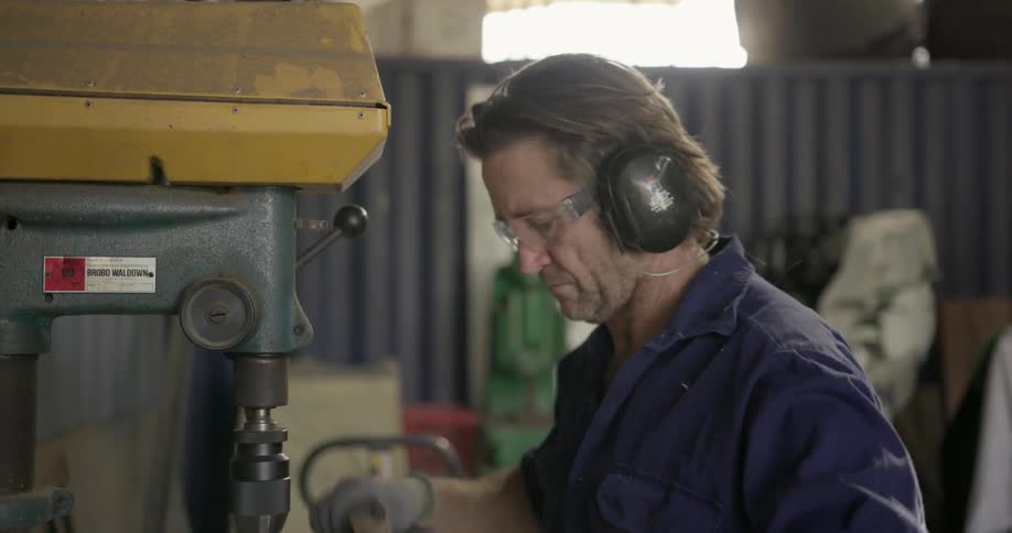 A carpenter drills a hole in a piece of wood