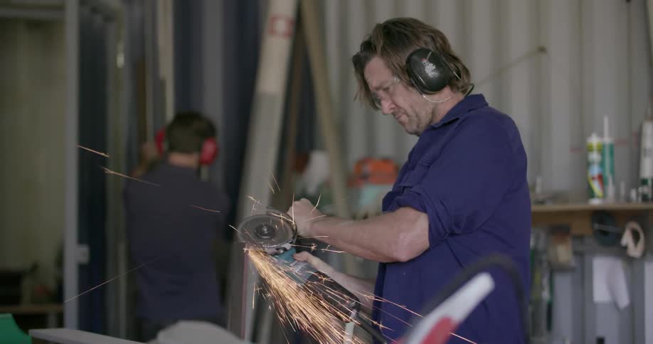 Man grinds a piece of metal as sparks shower around him