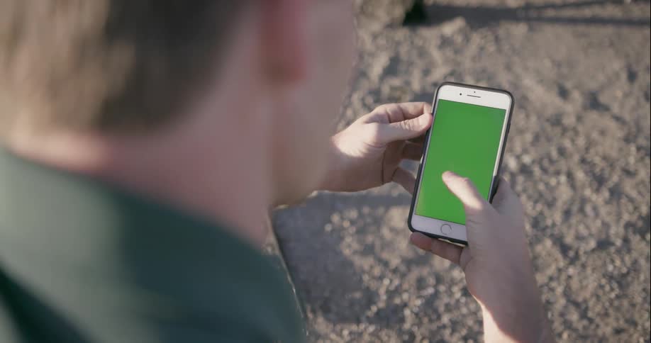 A man uses a smartphone outside on a sunny day