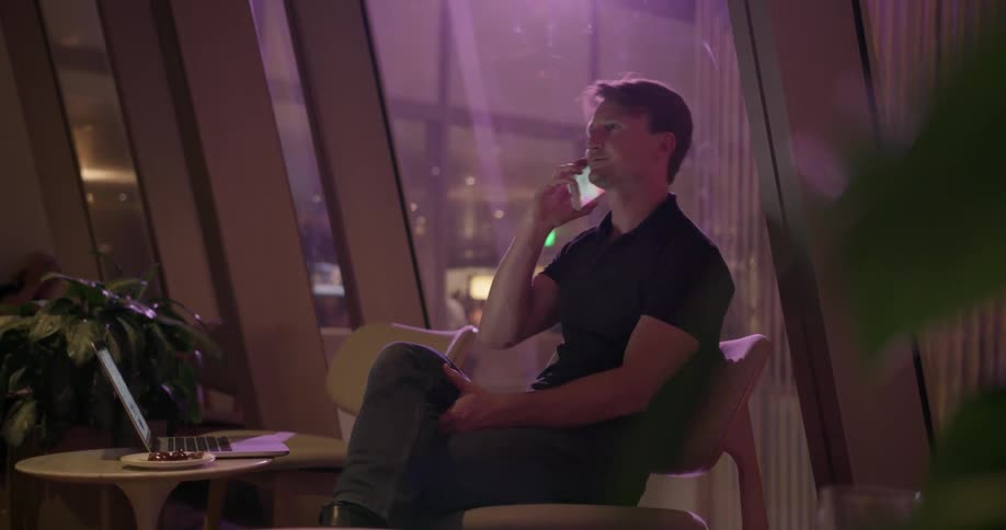 A man sits in a lounge talking on his phone