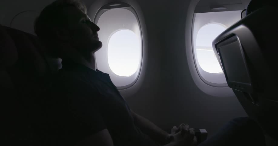 Man sitting in seat on airplane resting head back with eyes closed