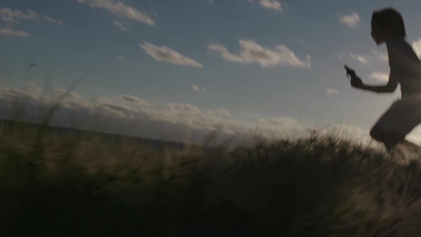 A child holding a gun is running in a field