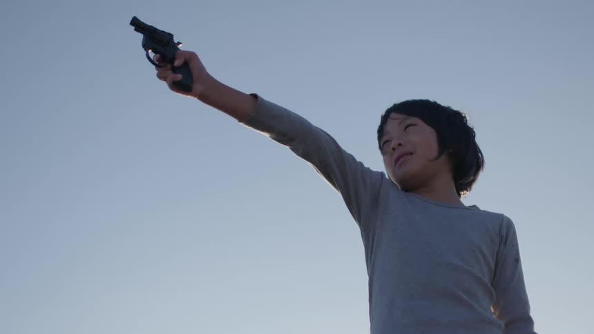 A young girl points a gun
