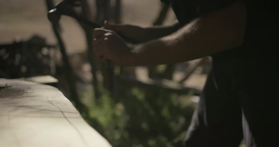 A man chisels at a piece of wood